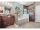 Bright bathroom featuring a soaking tub under a arched window and a separate glass enclosed shower at 3711 Half Moon Dr, Orlando, FL 32812