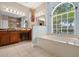 Bathroom with a garden tub, vanity with a stool, two mirrors, and an arched window at 3711 Half Moon Dr, Orlando, FL 32812