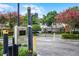 A gated entrance to a neighborhood with a security system, lush trees, and flowering shrubs at 3711 Half Moon Dr, Orlando, FL 32812