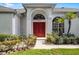 Close-up of a home's entrance features an arched doorway, red doors, and manicured landscaping at 3711 Half Moon Dr, Orlando, FL 32812