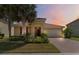 Charming single-story home with a tile roof, lush landscaping, and a brick driveway at sunset at 3906 Carrick Bend Dr, Kissimmee, FL 34746