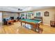 Spacious game room with a billiard table, a cozy brick fireplace, and hardwood floors for entertainment and relaxation at 400 Timbercove Pl, Longwood, FL 32779