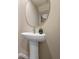 Stylish powder room features a pedestal sink with modern faucet, decorative mirror, and neutral wall paint at 5641 Brosnan Rd, St Cloud, FL 34771