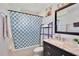 Bathroom features a stylish vanity with mirror and a shower with patterned curtain and rod at 8709 Knightsbridge Ct # B, Kissimmee, FL 34747
