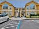 Exterior view of a sunny yellow condominium building with two stories and covered walkways to the entrance at 8709 Knightsbridge Ct # B, Kissimmee, FL 34747