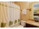 The bathroom features a granite vanity top, mirror, toilet and shower with a patterned curtain at 1156 Castle Pines Ct, Reunion, FL 34747