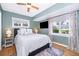 This bedroom is well-lit with windows, a ceiling fan, and features wood flooring and calming color scheme at 1301 Fahnstock St, Eustis, FL 32726