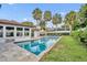 A backyard pool with lounge chairs and a patio surrounded by green grass and palm trees at 137 N Spring Lake Dr, Altamonte Springs, FL 32714