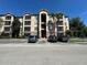 Exterior of a multi-story condo building with palm trees, covered walkways, and parking lot in front at 1370 Tuscan Ter # 2202, Davenport, FL 33896