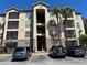 Multi-story condo building with palm trees, covered walkways, and parking lot in front at 1370 Tuscan Ter # 2202, Davenport, FL 33896