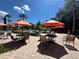 Relaxing pool area with tables, chairs, sun umbrellas, and lush landscaping on a sunny day at 1370 Tuscan Ter # 2202, Davenport, FL 33896