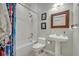 Charming bathroom with a pedestal sink, tub, and framed mirror, complemented by stylish decor at 14128 Bramble Bush Ct, Orlando, FL 32832