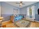 A cozy bedroom with blue walls, wood floors, a ceiling fan and an eye-catching area rug at 14128 Bramble Bush Ct, Orlando, FL 32832