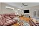 Cozy living room with hardwood floors, a leather sofa, and lots of natural light from two windows at 14128 Bramble Bush Ct, Orlando, FL 32832