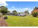 Spacious backyard features lush green grass, a screened lanai, and a charming white fence at 1505 N Lake Mirror Nw Dr, Winter Haven, FL 33881
