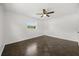An empty bedroom features a ceiling fan, closet and a large window, with hard wood floors at 1505 N Lake Mirror Nw Dr, Winter Haven, FL 33881