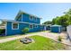 A two-story blue home features a brick-paved patio and fire pit nestled in the green grass of the backyard at 1609 E Kaley Ave, Orlando, FL 32806