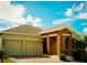 The home's facade features a two-car garage and a welcoming brick-columned entryway at 1889 Blissful Dr, Kissimmee, FL 34744