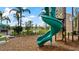 Community playground with a green spiral slide and wood chip ground cover under a bright blue sky at 2273 White Buffalo St, Apopka, FL 32703