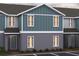New two story townhome displaying board and batten details, gray paint and a covered entry in a manicured lawn at 2416 Cabinwood Range Way, Eustis, FL 32726