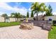 This backyard features a brick paver patio, fire pit, custom seating, lush lawn and tropical landscaping at 2896 Matera Dr, St Cloud, FL 34771