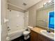 This cozy bathroom features a shower-tub combo and a sink with a wood cabinet and a large mirror at 306 Snook Way, Kissimmee, FL 34759