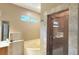 Modern bathroom featuring a shower stall with natural stone trim, soaking tub and window at 3100 Pine Needle Trl, Kissimmee, FL 34746