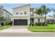 Charming two-story home featuring stone accents, a two-car garage, and a well-manicured lawn with palm trees at 369 Ocean Course Ave, Davenport, FL 33896