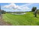 Expansive backyard view showcasing a serene pond, lush green grass, and neighboring houses at 369 Ocean Course Ave, Davenport, FL 33896
