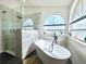 Bright bathroom featuring a glass shower, modern tub, large window, and neutral tile at 3708 Beaver Ridge Dr, Orlando, FL 32829