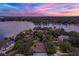 Breathtaking aerial view of a home on the water with surrounding trees at sunset at 446 Alberta Dr, Winter Park, FL 32789