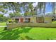 Landscaped front yard with trees, lawn, and stone wall leading to a single-story home at 446 Alberta Dr, Winter Park, FL 32789