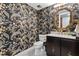 Beautifully decorated half bath with gold fixtures, mosaic floors, and floral wallpaper at 446 Alberta Dr, Winter Park, FL 32789