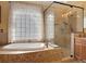 Bathroom featuring a glass block window, a tub, and glass-enclosed shower at 448 Warrior Trl, Deltona, FL 32725