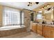Well-lit bathroom with tiled floors, glass shower, soaking tub, and granite double vanity at 448 Warrior Trl, Deltona, FL 32725