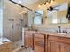 Bathroom featuring dual sinks, granite counters, and a glass-enclosed shower at 448 Warrior Trl, Deltona, FL 32725