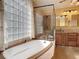 Bathroom showcasing a glass block window, tub, and glass-enclosed shower at 448 Warrior Trl, Deltona, FL 32725
