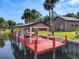 Aerial view of dock with a red floor on calm water, surrounded by lush landscaping at 448 Warrior Trl, Deltona, FL 32725
