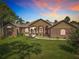 Charming single-story home featuring brick accents, manicured lawn, and inviting curb appeal under a sunset at 448 Warrior Trl, Deltona, FL 32725