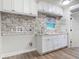 Bright laundry room featuring white cabinets, granite counters, a decorative backsplash, and modern appliances at 448 Warrior Trl, Deltona, FL 32725
