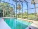 Large screened-in pool surrounded by lush greenery and water views beyond at 448 Warrior Trl, Deltona, FL 32725