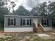 Charming single-story home with gray siding, black shutters, and a welcoming front porch and steps at 45814 Lake St, Paisley, FL 32767