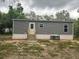 Exterior view of a cozy home with gray siding, front door access, and outdoor AC unit at 45814 Lake St, Paisley, FL 32767
