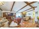 Spacious living room featuring wood floors, a stone fireplace, and exposed ceiling beams at 4799 Lighthouse Rd, Orlando, FL 32808