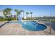 Inviting hot tub surrounded by lush palm trees and pristine landscaping near calm waters at 4802 Lullaby Ln, Kissimmee, FL 34746