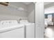 Functional laundry room with white washer and dryer, plus overhead shelving at 4802 Lullaby Ln, Kissimmee, FL 34746