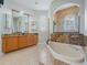 Elegant bathroom featuring a large soaking tub, granite countertop, and custom wood cabinetry at 4951 Parkview Dr, St Cloud, FL 34771