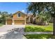 Charming two-story home with manicured lawn, mature trees, and three-car garage on a sunny day at 4951 Parkview Dr, St Cloud, FL 34771
