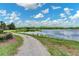 Scenic walking path alongside a calm lake, framed by lush greenery and a partly cloudy sky at 4951 Parkview Dr, St Cloud, FL 34771