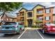 A modern apartment building exterior with balconies, parking, and colorful paint on a partly cloudy day at 6029 Westgate Dr # 726, Orlando, FL 32835